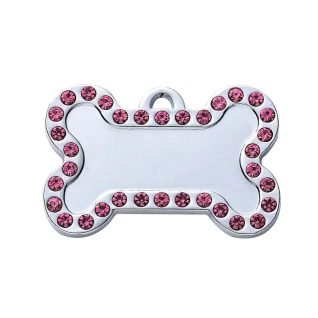 Dog tag shaped like a bone with pink gemstones on a white background